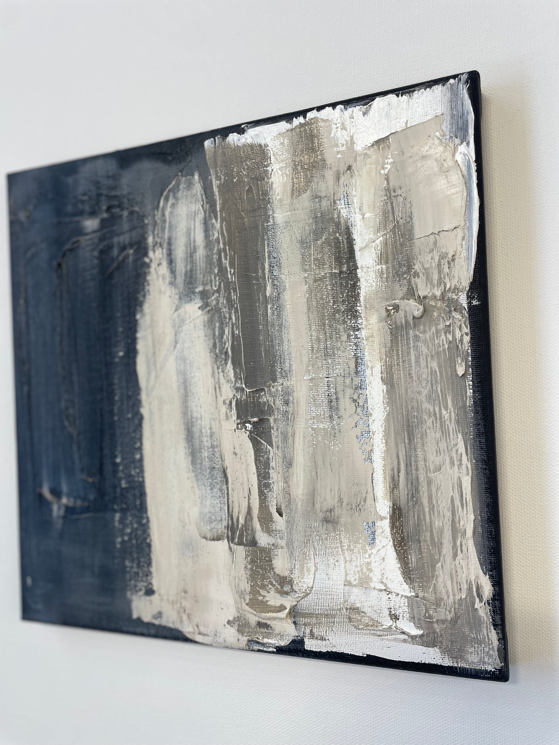 Abstract art piece with black and white brush strokes on a white wall.