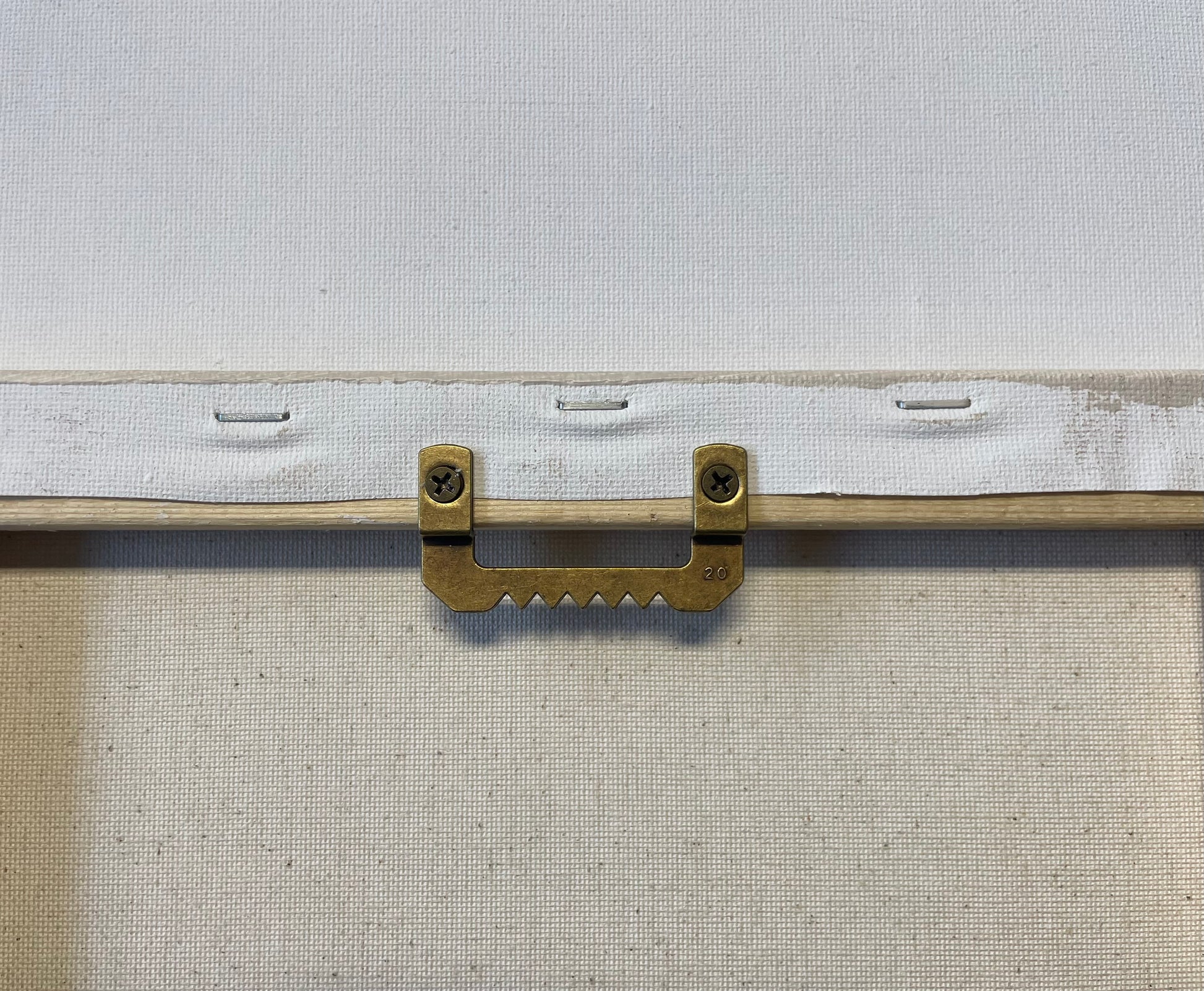 Metal bracket attached to a white frame with a textured background