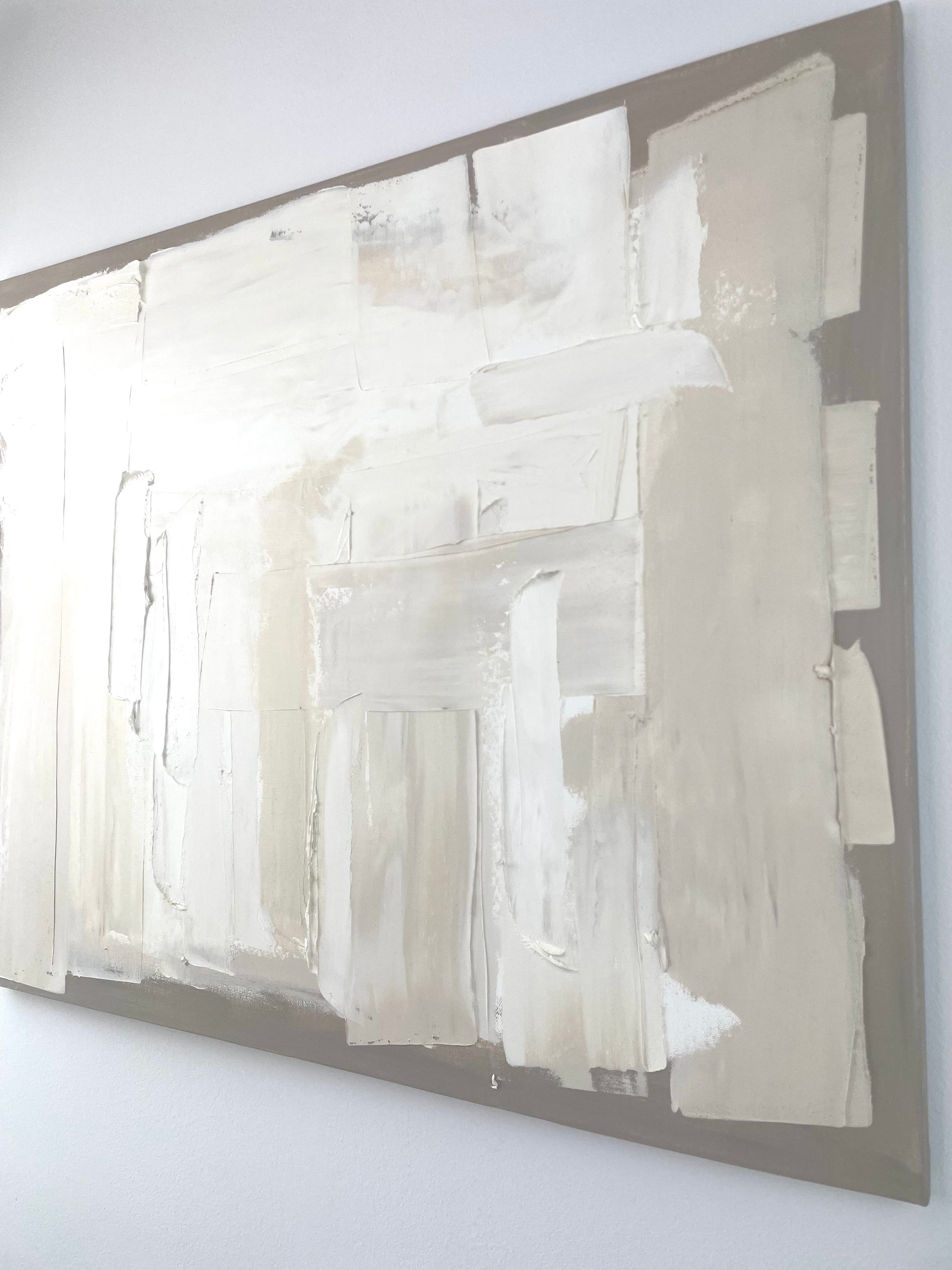 Abstract art piece with white and gray tones on a white wall