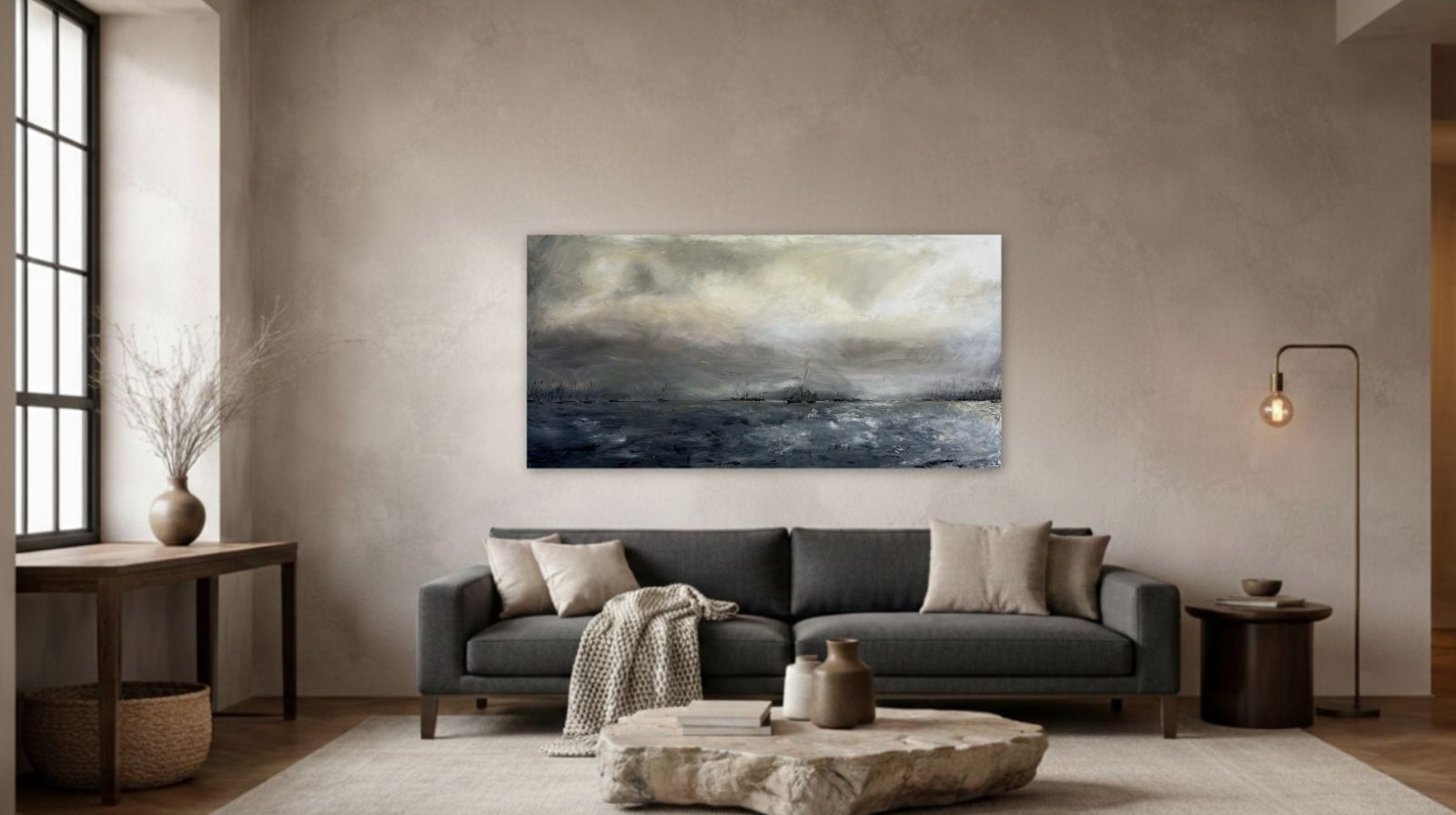 Narragansett Bay 24x48 oil painting by Caroline Adrienne styled above a modern charcoal grey sofa in a minimalist room with warm textured walls and a stone coffee table.