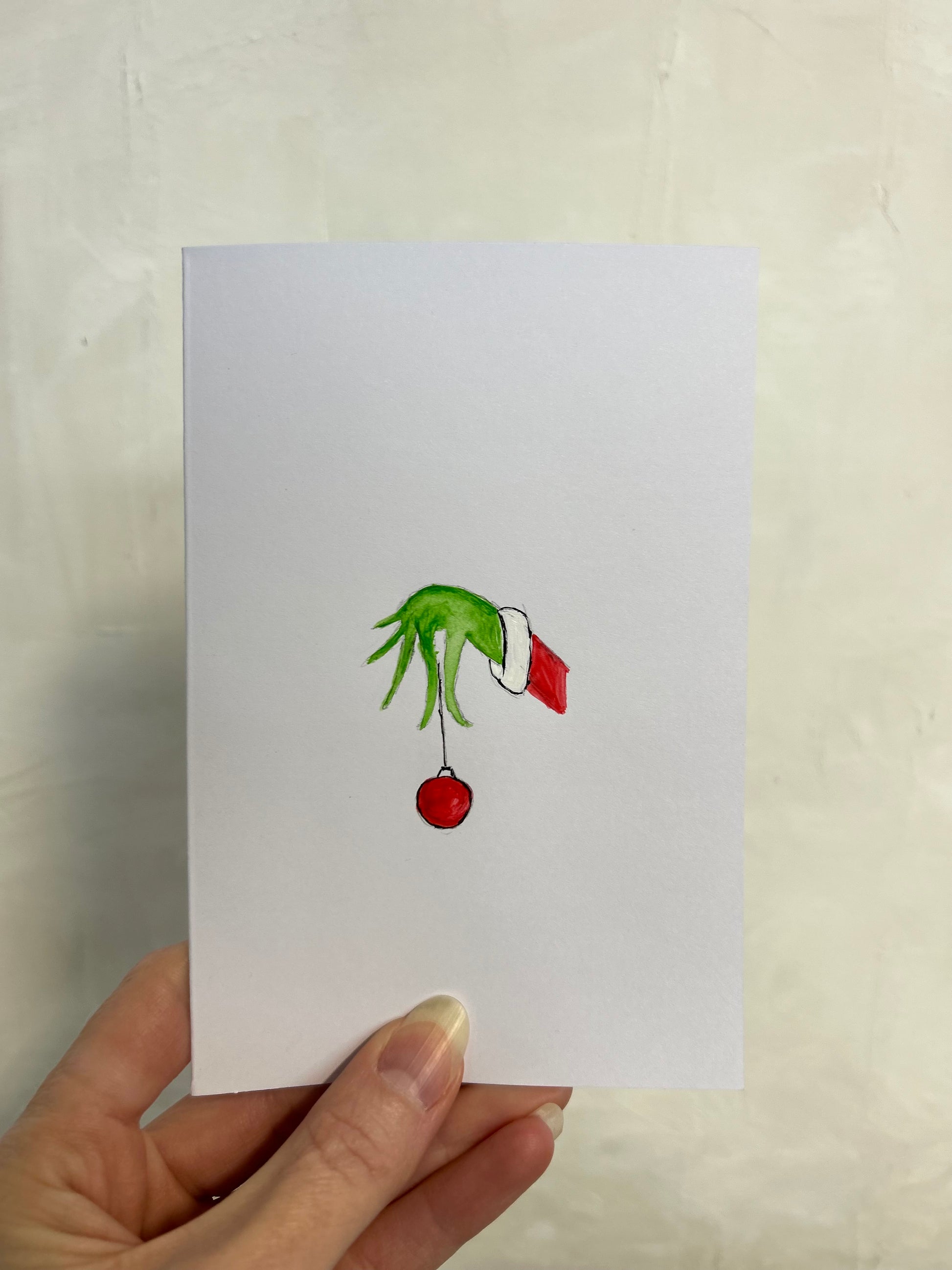 Hand holding a card with a green hand holding a red ball on a white background